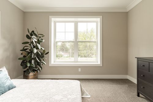 Bedroom with a white bed, potted plant and neutral carpet