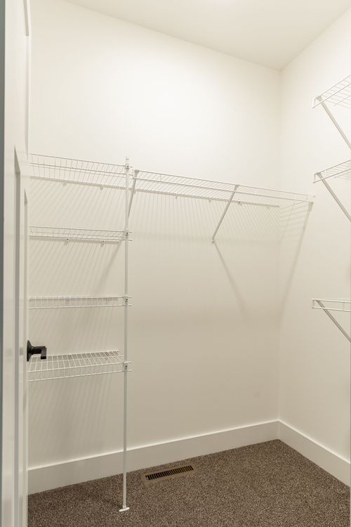 Empty walk-in closet with white wire shelving and carpet flooring
