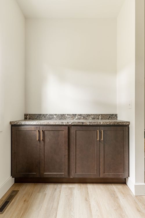 Built-in laundry nook with dark wood cabinetry and a granite counter