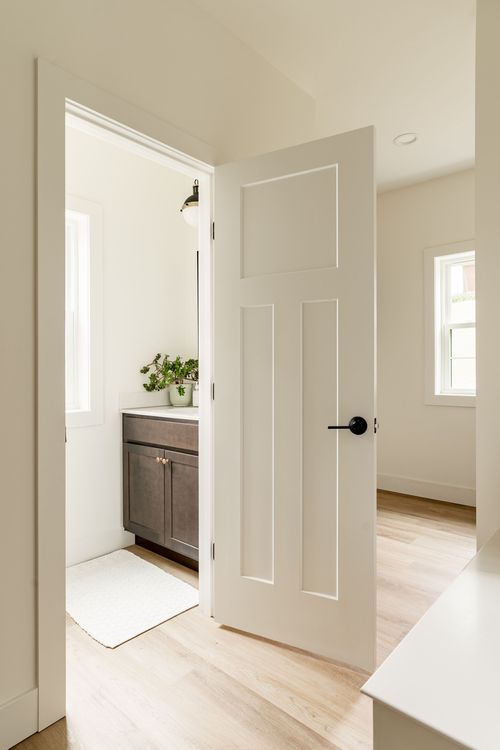 Hallway view through an open door into a bathroom with a gray vanity