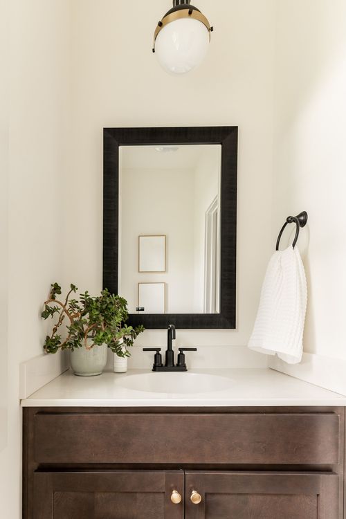 Powder room vanity with a black-framed mirror, pendant light and towel ring