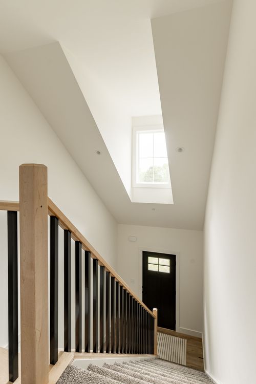 Stairwell with a skylight, wood-and-black railing and the front entry below