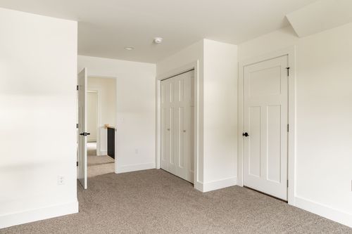 Empty bedroom with white closet doors and carpet flooring