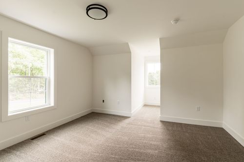Empty carpeted bedroom with a vaulted ceiling and window nook