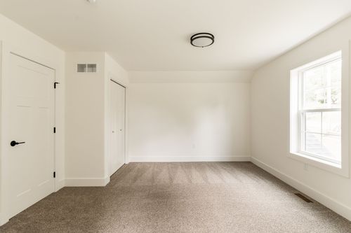 Empty bedroom with a closet, window and vaulted ceiling