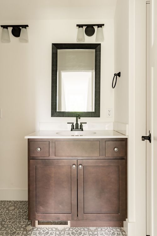 Powder room vanity with a dark wood cabinet, black mirror and sconce lighting