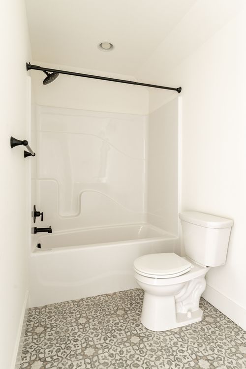 Bathroom with a white soaking tub, black fixtures and patterned tile flooring