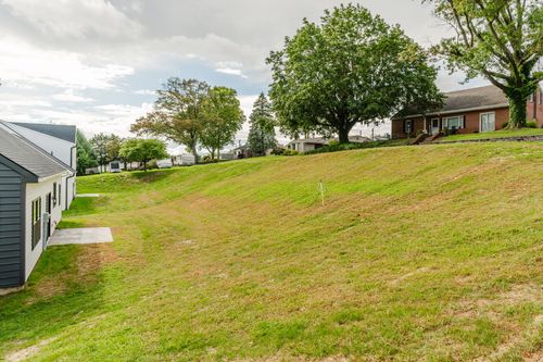 Aerial view of a sloped grassy lawn leading down toward a small-town neighborhood