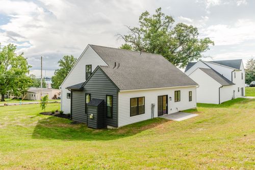 Rear exterior of a white two-story home with black trim and a grassy sloped yard