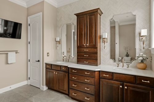 Marble bathroom counter with dark wood drawers and patterned floor tile
