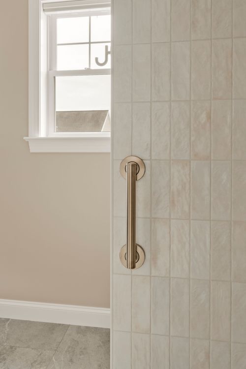 Close view of a brass shower door pull with a window showing a neighboring rooftop