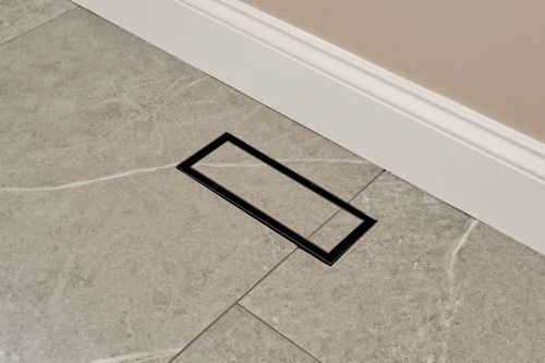 Close view of a black floor outlet cover on patterned tile flooring