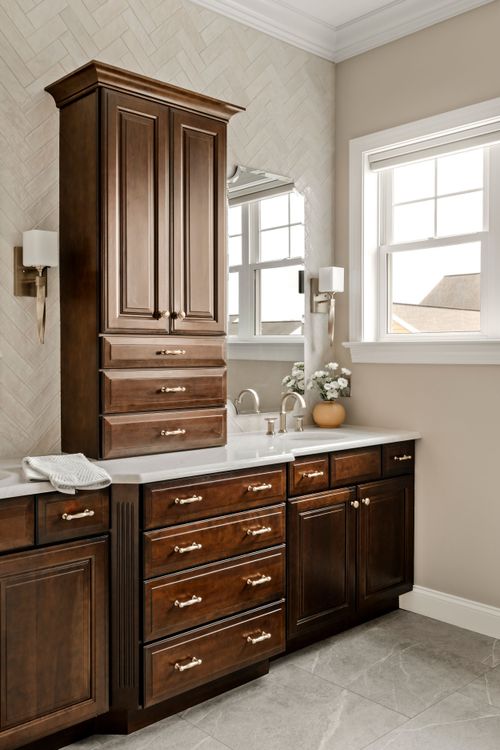 Double vanity bathroom with dark wood cabinetry, marble counters and herringbone tile backsplash