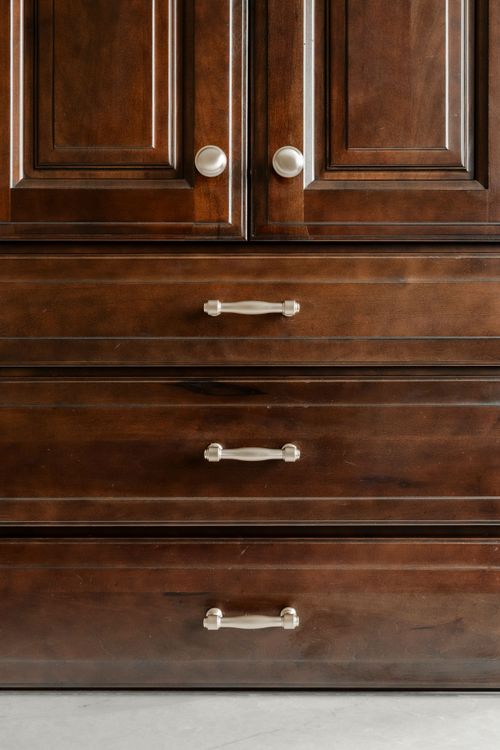 Double vanity with dark wood cabinets, a linen tower and herringbone tile backsplash