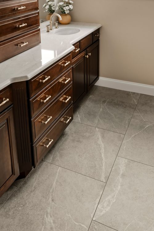 Bathroom vanity with an arched mirror, brass sconces and herringbone tile backsplash