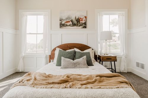 Bedroom with a wood bed, bedside lamp and framed landscape painting