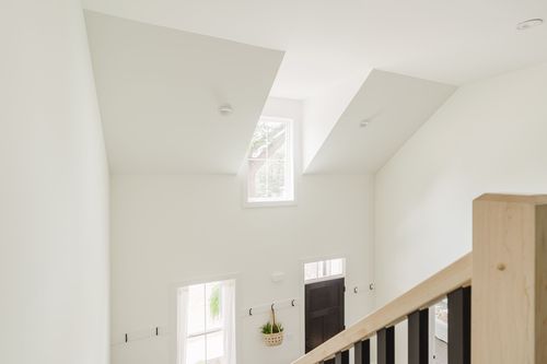 Vaulted stairwell landing with dormer skylights and a black front door