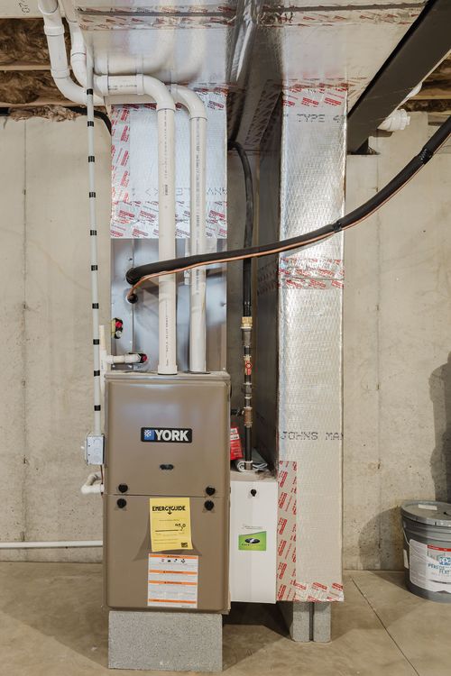 Close view of a York gas furnace with insulated ductwork in an unfinished basement