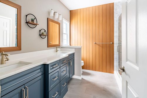 Bathroom with a navy blue vanity, wood-framed mirrors and a wood plank accent wall in Lititz