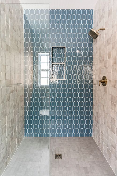 Walk-in shower with blue honeycomb tile, a window and gold shower fixtures
