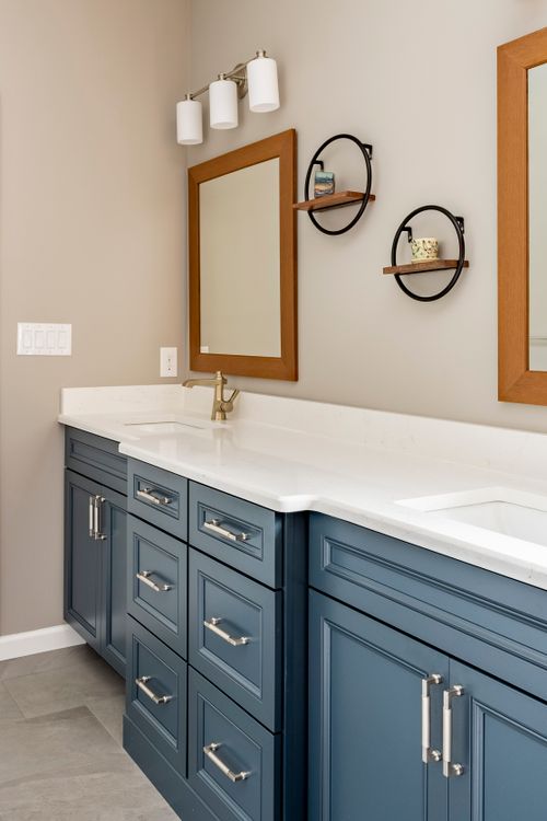 Close view of navy blue double vanity cabinets with brushed nickel hardware and round wall shelves