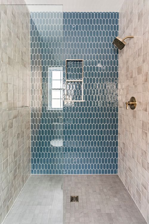 Walk-in shower with blue honeycomb tile, a window niche and gold fixtures