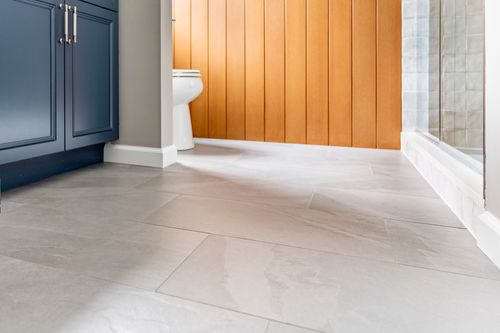 Close view of tile flooring beside a blue vanity and wood plank accent wall