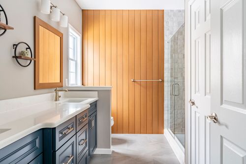 Bathroom with a blue vanity, wood plank accent wall and a walk-in shower
