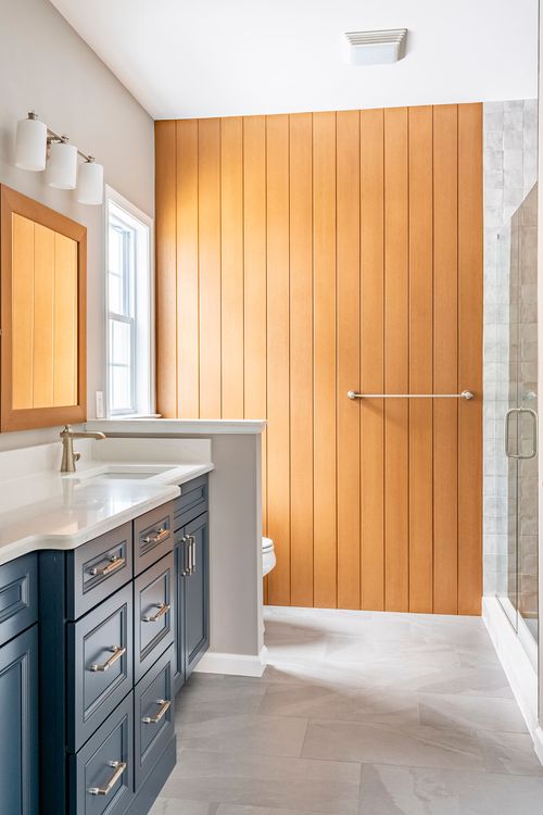 Wood plank accent wall with a towel bar leading to a glass-enclosed shower
