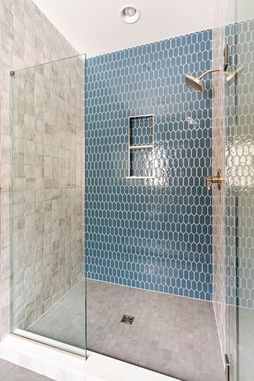 Walk-in shower with blue honeycomb tile, a built-in niche and gold fixtures