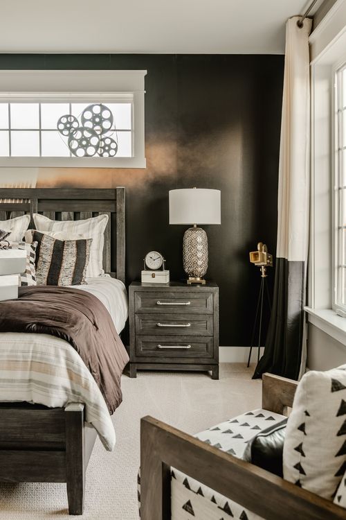 Bedroom nightstand with lamp, clock and vintage camera against a black accent wall
