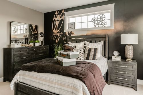 Bedroom with black accent wall, dark wood dresser and mirror beside a black nightstand