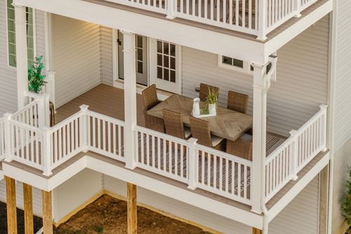 Aerial view of an upper deck with a dining table and wicker chairs