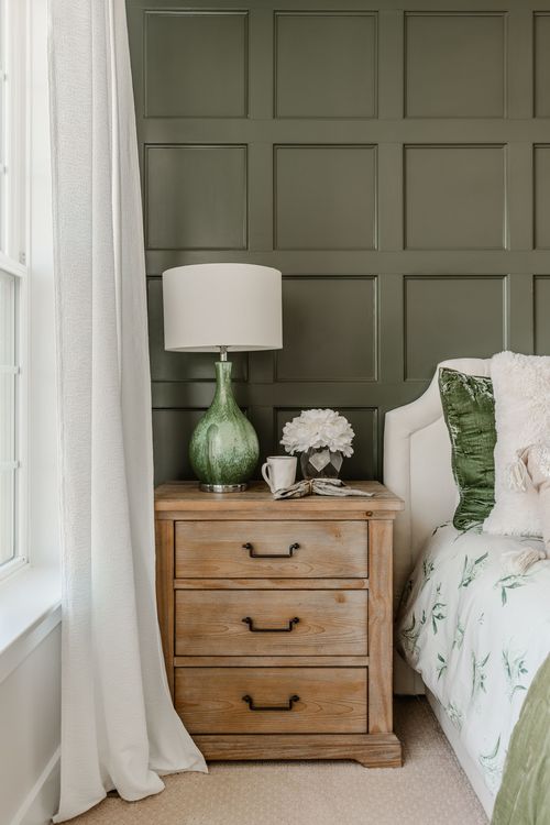 Bedroom with black door, wood dresser, round mirror and gray accent chair