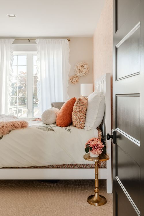 Girl's bedroom with whimsical floral wall decor, rattan pendant and white ruffled curtains