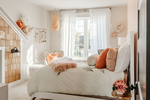 Kids bedroom with peach herringbone accent wall, white bed and orange floral pillows