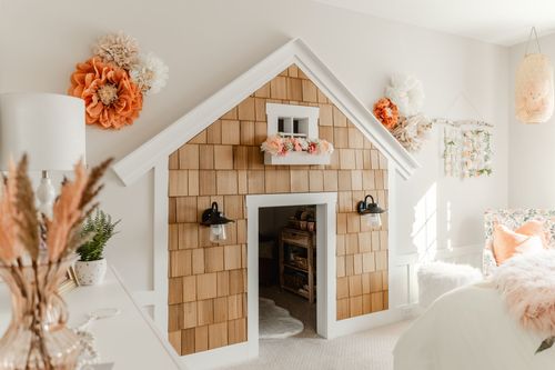 Kids bedroom desk against a peach herringbone wall beside a white bed with shag throw