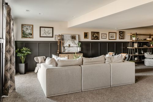 Basement living room with sectional sofa, gallery wall and dark wainscoting