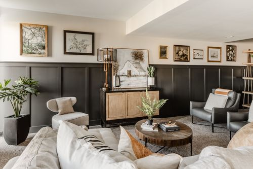 Basement family room with dark wainscoting, gallery wall and a wet bar in view