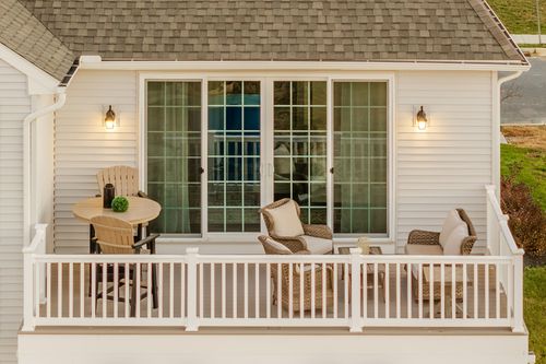 Covered deck with a wicker sofa and chairs facing sliding glass doors