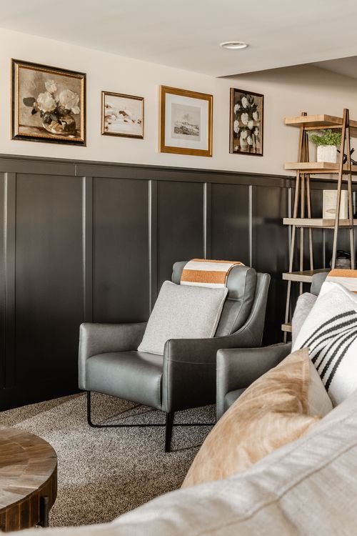 Basement seating with a gray leather armchair, ladder shelving and framed art