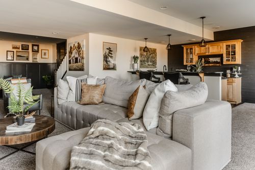 Basement family room with a gallery wall, wood cabinet and sectional sofa