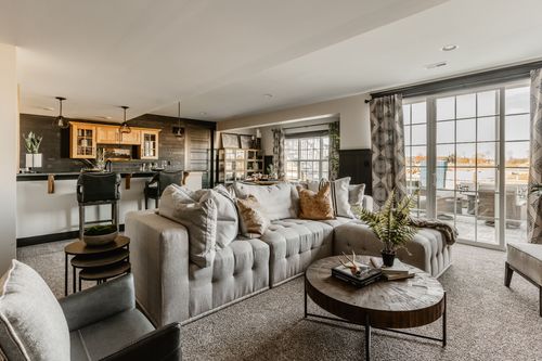 Open basement living room and kitchenette with sectional sofa and round coffee table