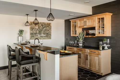 Basement wet bar with black shiplap wall, wood cabinetry and leather stools
