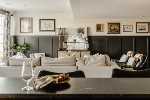 Basement living room with sectional sofa, gallery wall and wet bar beyond