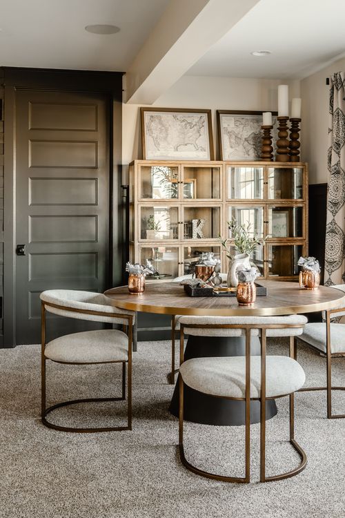 Basement dining nook with a round table, glass cabinet and black door