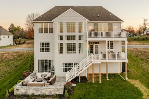 Aerial rear view of a custom home with layered decks surrounded by fall foliage