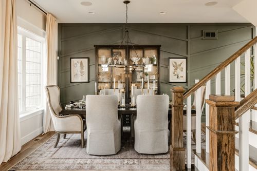 Close view of a framed botanical print beside a glass-front hutch on a green paneled wall