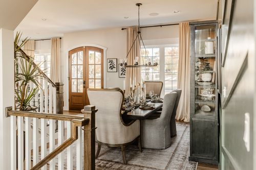 Staircase landing with white balusters, a wood rail and a glass front door beyond