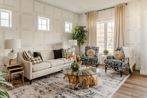Living room with wainscoted walls, a beige sofa and a round glass coffee table